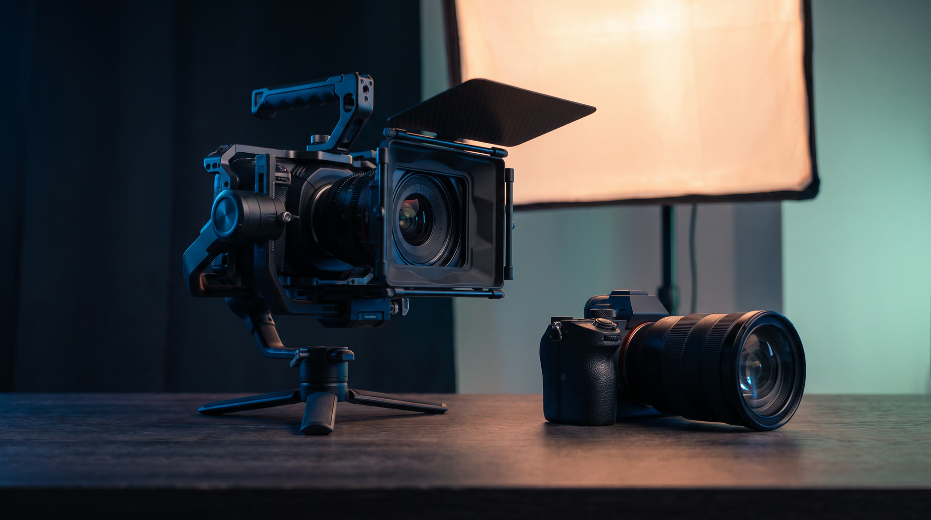 Filmkamera på gimbal och systemkamera i en mörk studio